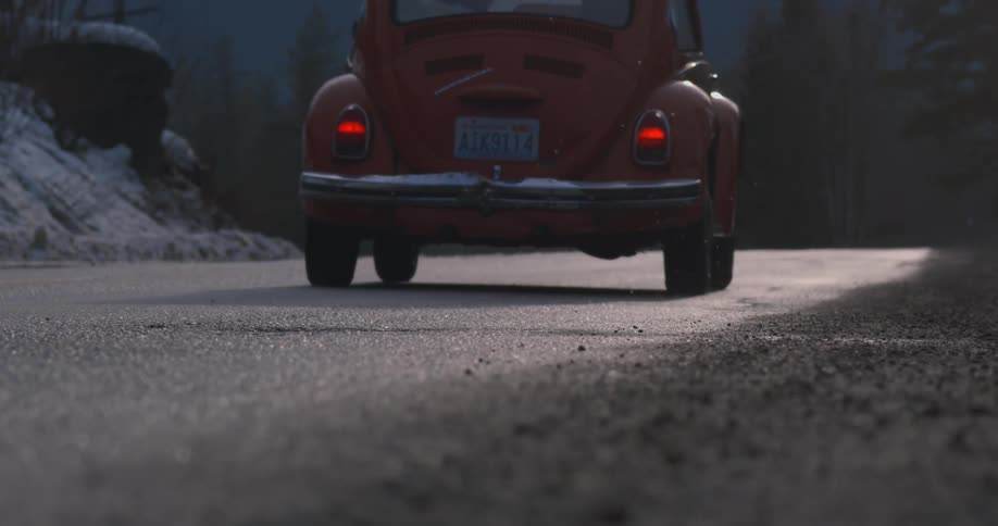 A person driving a volkswagen beetle drives along a highway