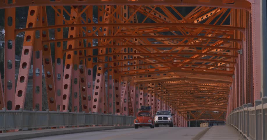 Vintage Bug drives across an orange bridge