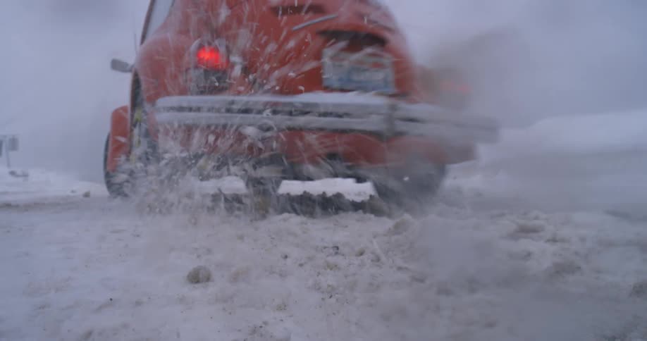 A car with snow tires spinning out and spitting snow
