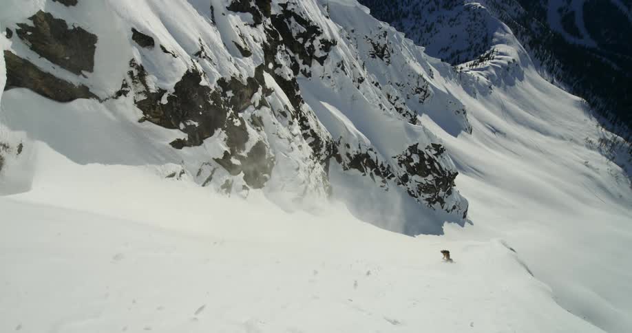 Snowboarder on steep slope in rugged mountains
