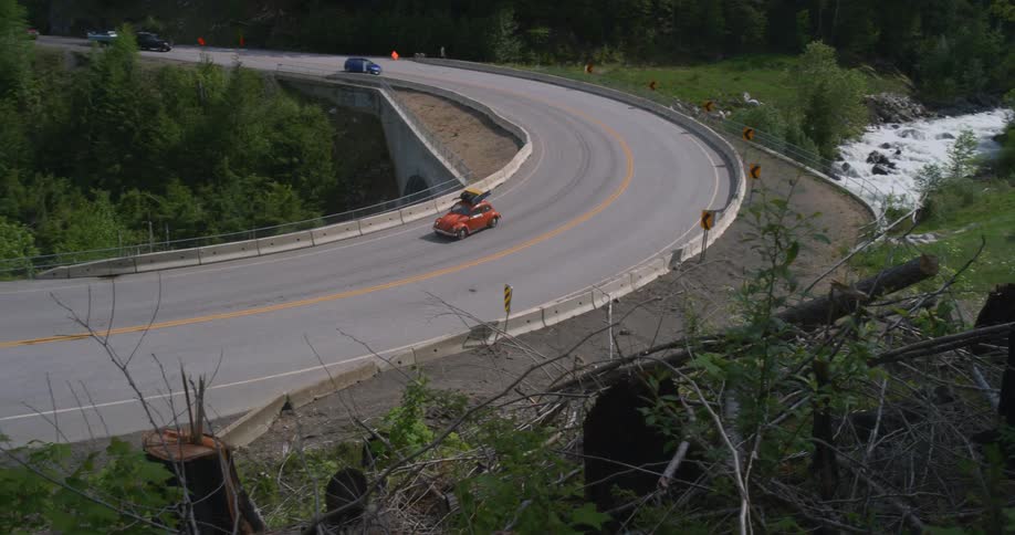 A vintage car drives through a forested area