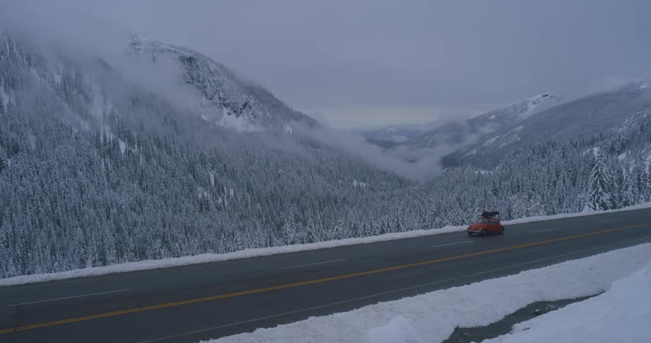 A car driving up a road next to a snow covered forest