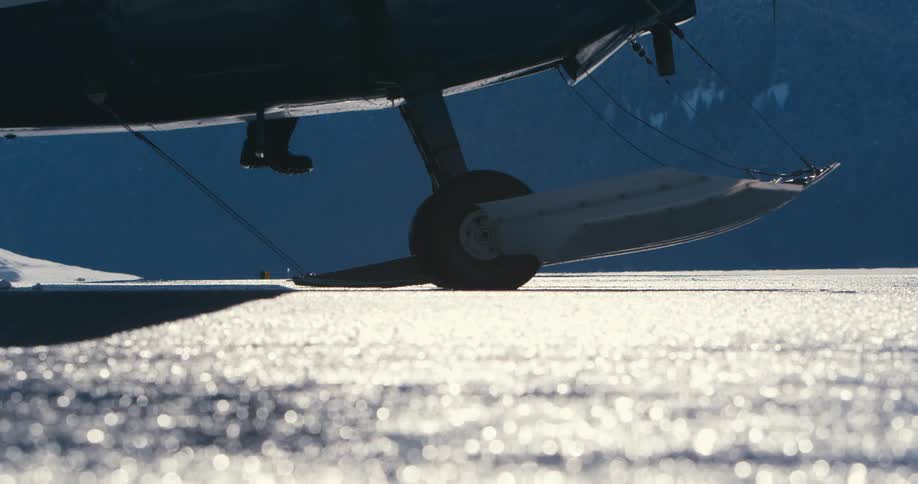 A pilot climbs into a plan parked on an icy tarmac