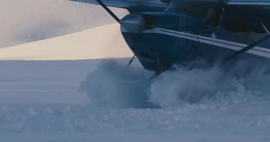 Small airplane taking off from snow covered field