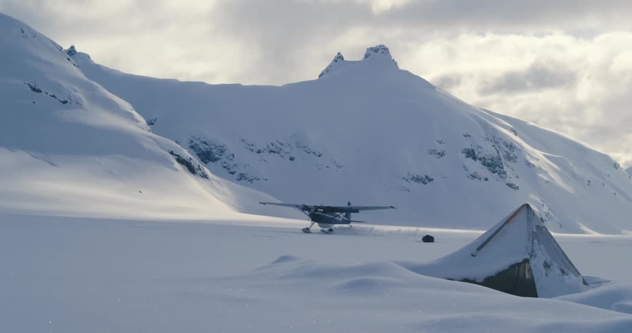 An airplane traveling in snowy mountains on a cloudy day