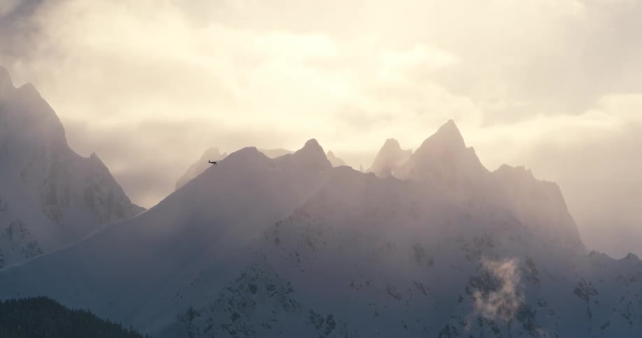 A helicopter flying over a snowy mountain range