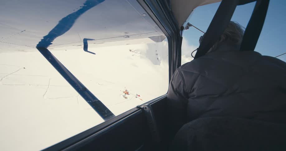 Pilot landing aircraft near small base camp in snowy mountains