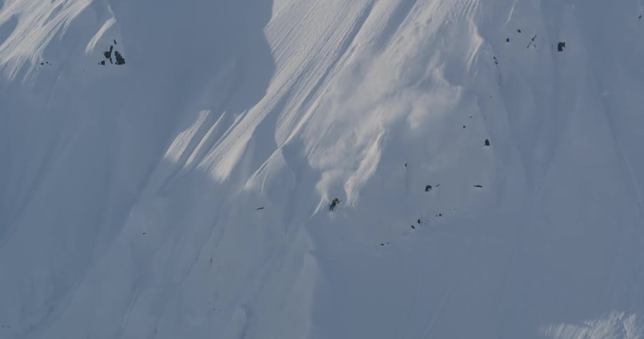 A lone skier skis down the side of a snow covered mountain