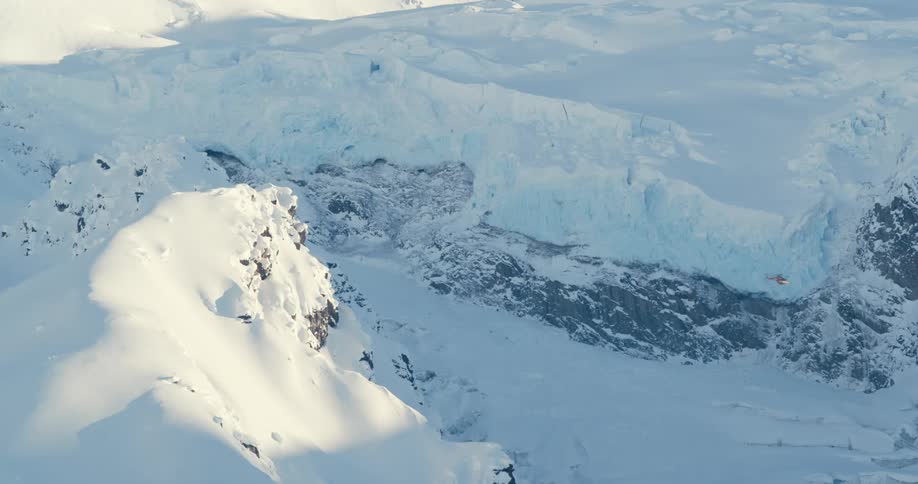 Helicopter flies in front of snow covered mountains