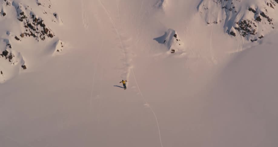 An aerial view of a skier gliding down a snowy mountainside