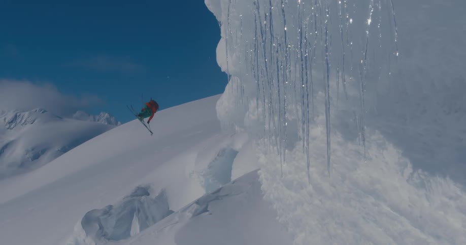 A skier goes over a jump in snowy mountains