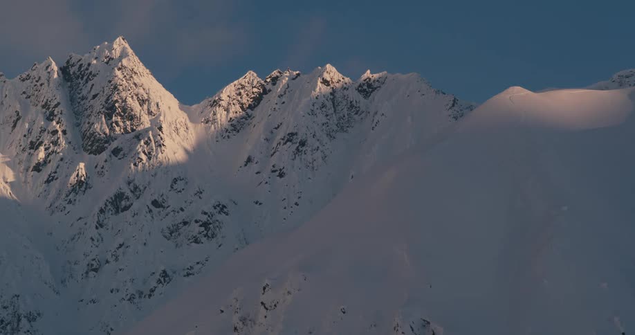 Clouds move over snow covered mountain peaks