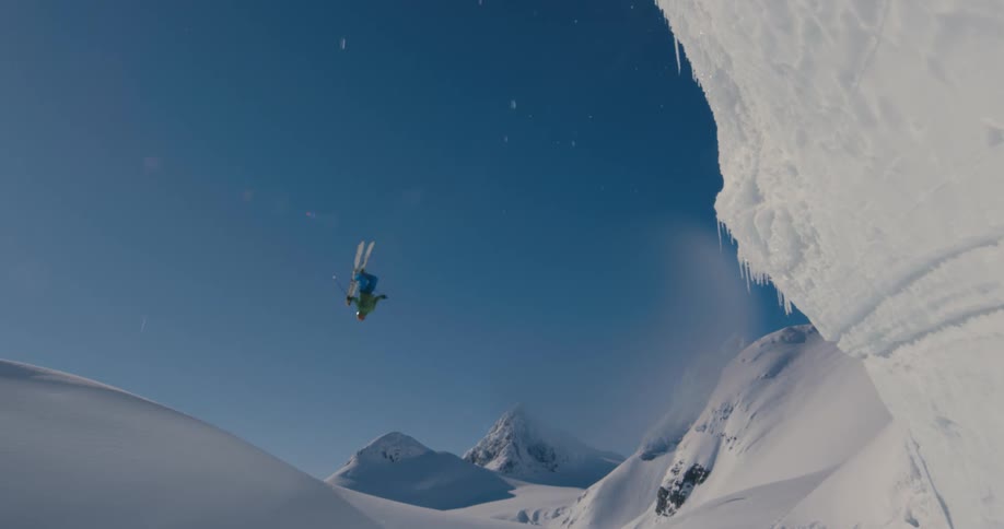 Skier jumps over a chasm in the snow covered slopes of a mountain