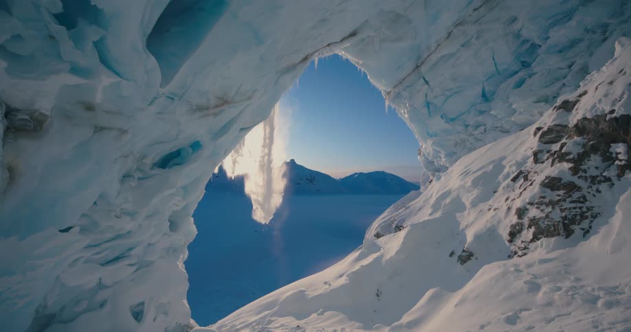 A skier jumps over a massive ice cave at dawn