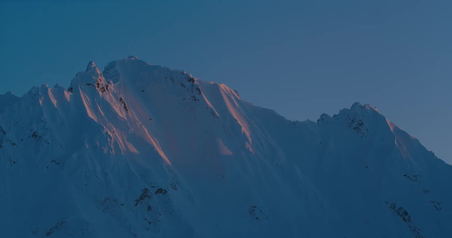 An exceptionally tall mountain range is completely covered in a layer of snow