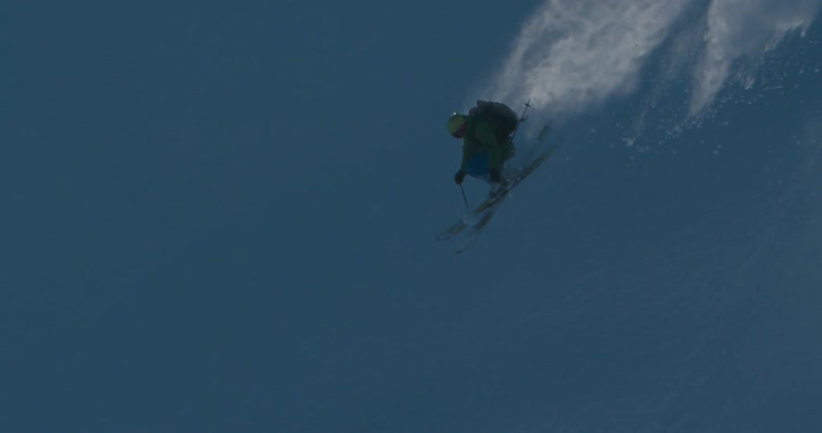 A skier slides off a block of compacted snow and is momentarily airborne before landing on the slope below