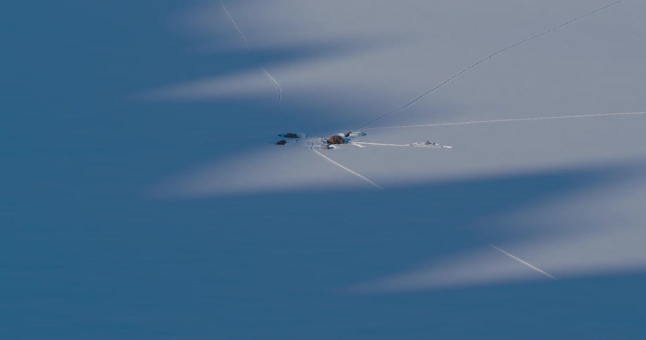 Tent base camp on the snow under the mountain peak shadows