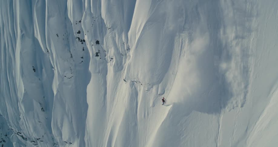 A skier skiing down a steep mountain slope