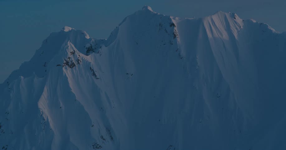 An aerial view of a snow covered mountain is displayed