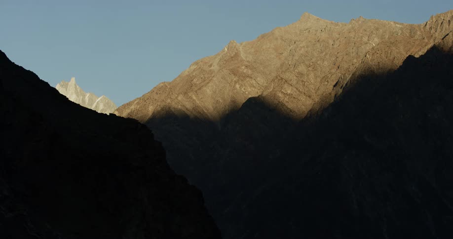 A mountain range with sunlight and shadow with the sky in the background