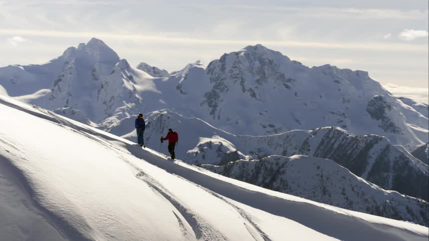 Aerial wrap around a pair of skiers on a high mountain ridge