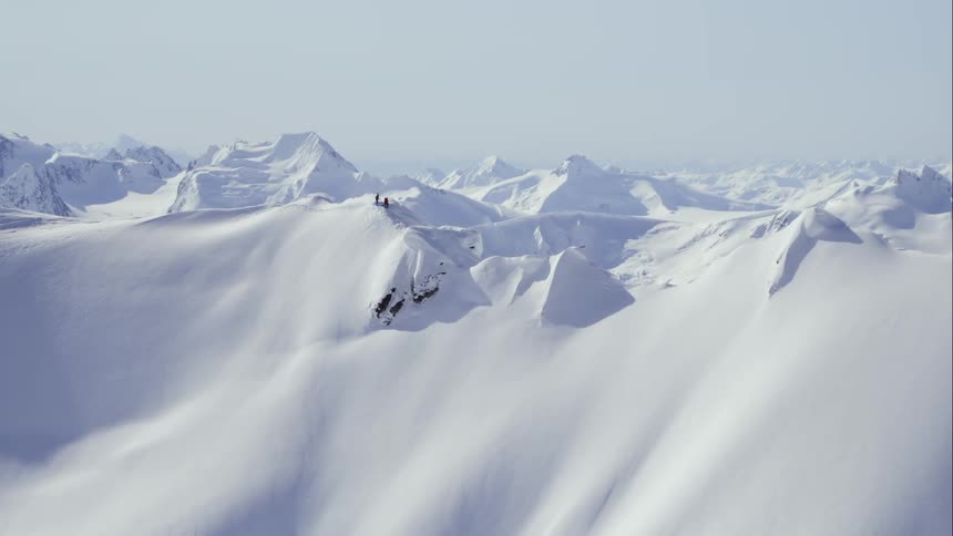 Aerial of two people on a mountain ridge above a huge vista