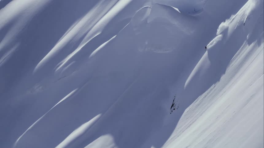 Aerial of a skier descending a huge mountain at high speed