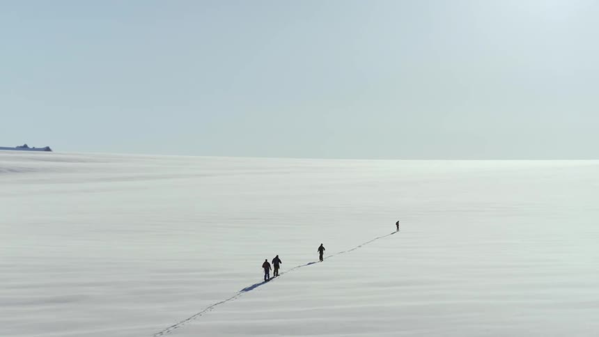 Aerial of group of skiers touring in a line over the vast snowfield