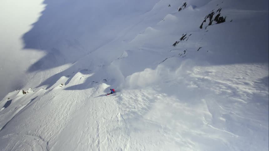 Aerial overhead of skier dropping into an extreme ski run