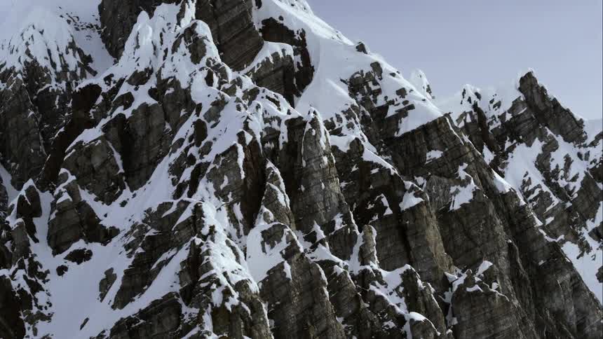 Aerial wrap around snowy mountain flanks