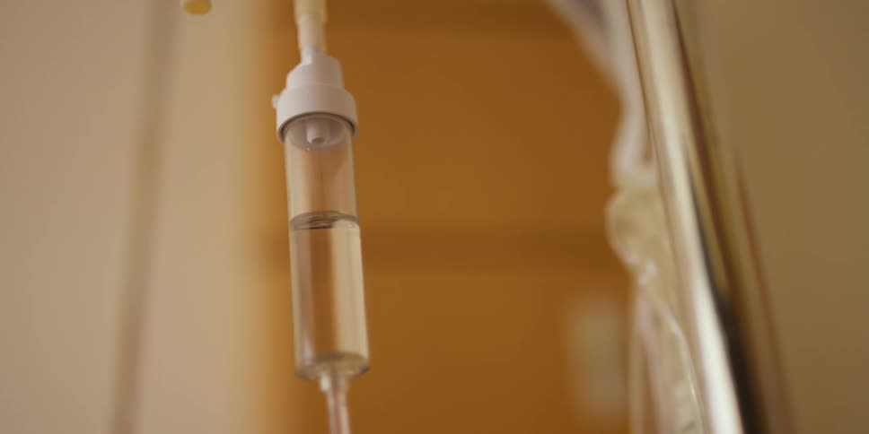 An iv drip next to a pole and a saline bag
