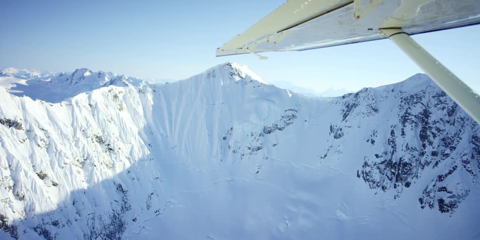 Aerial view of snow capped mountains against the cloudless blue sky seen from a plane