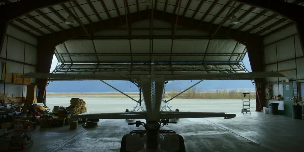 Airplane hangar door opens in front of small aircraft inside
