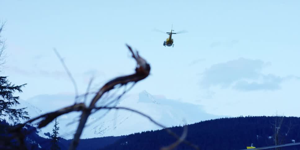 Yellow helicopter flying over the mountains at sunset