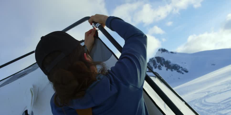A male pitching a tent on a snowy mountain