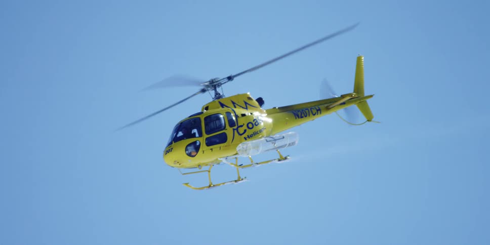 A helicopter is flying through the clear sky