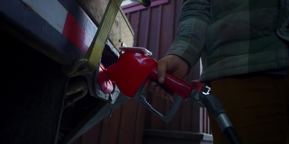 A person pumps gasoline into a vehicle