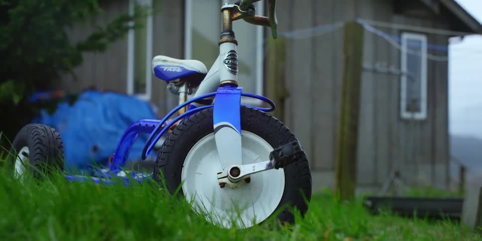 A blue tricycle outside on a grassy lawn