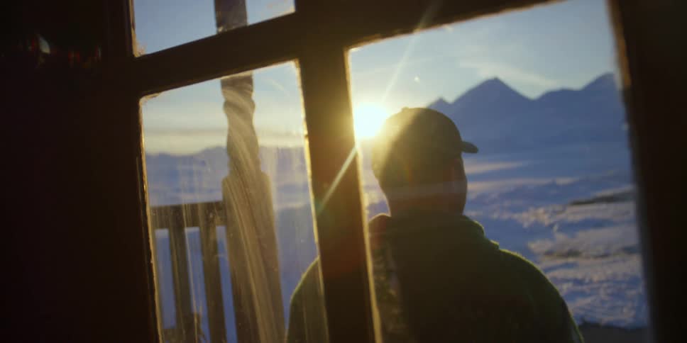 A person is standing outside a house at sunrise