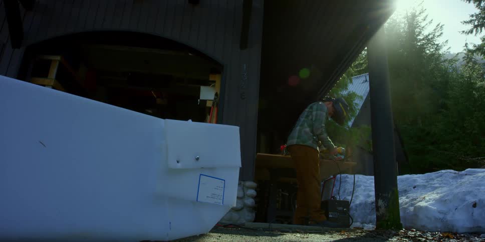 Man cuts metal with a power tool outside a house in the mountains at winter