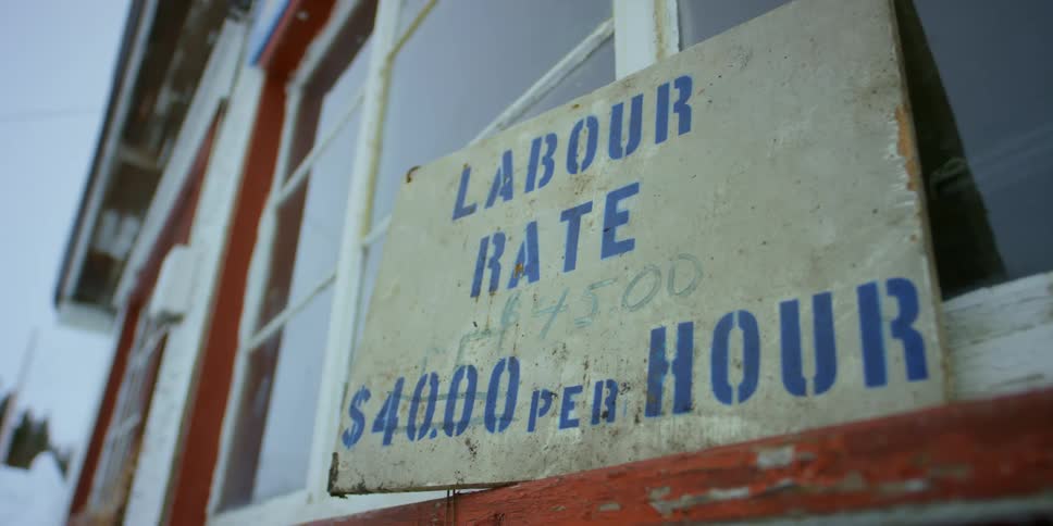 A small sign outside a business advertises pay rate for a job opening