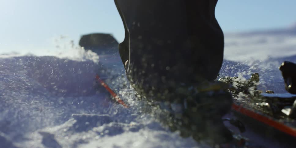A person wearing a ski boots securely latches their boot into the clips on their ski