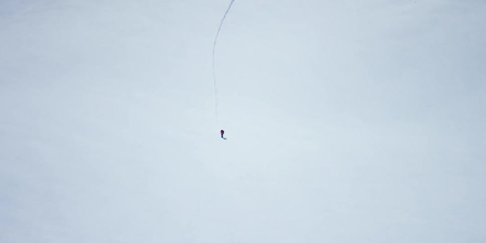 A snowboarder leaves a trail through freshly fallen snow