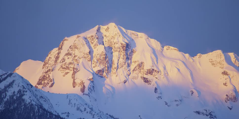 An aerial view of a snow covered mountain is displayed