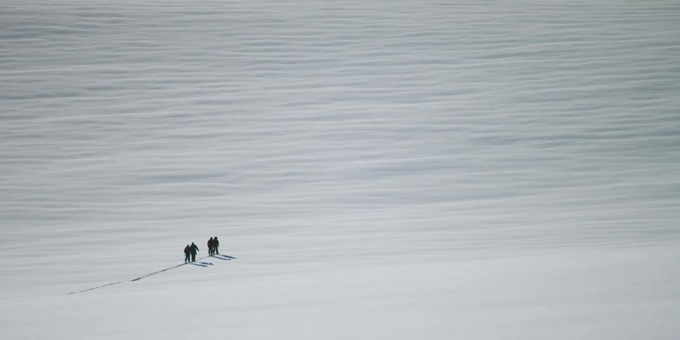 Group of people walk across snow