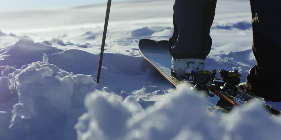 Person in ski boots steps onto skis in snow