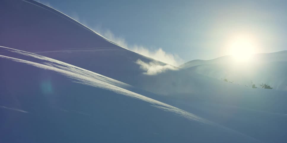 A skier gliding down a snowy mountainside on a sunny winter day