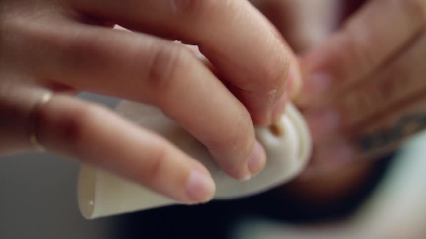 A woman folds pleats to form an asian dumpling