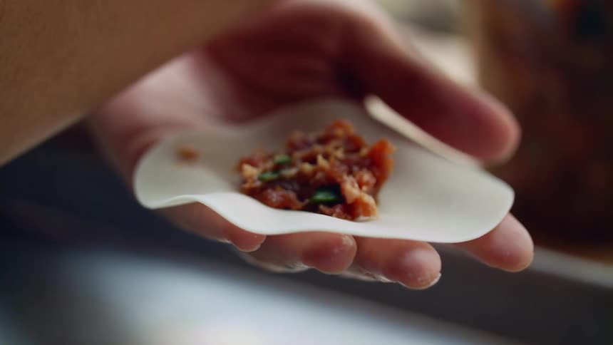 A woman at home stuffs dumplings