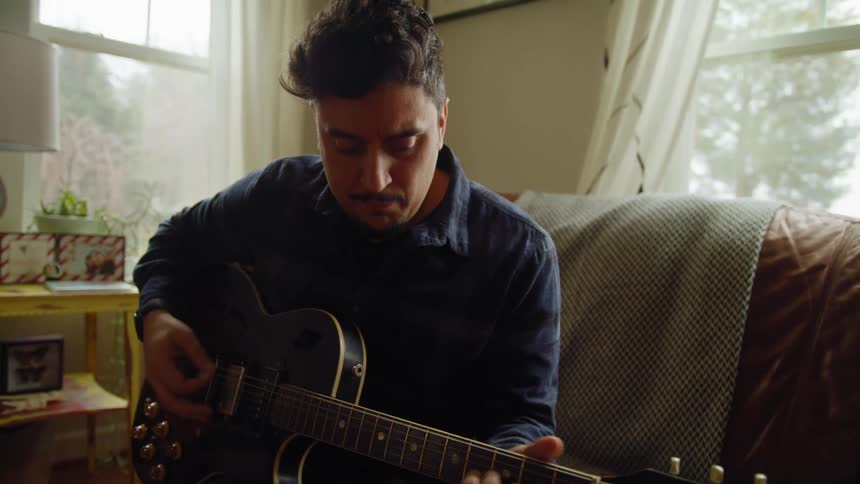 A man is playing guitar in a living room